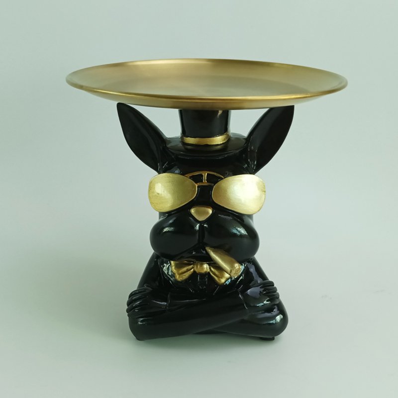 Siedząca figurka buldoga trzymająca okrągłą tackę