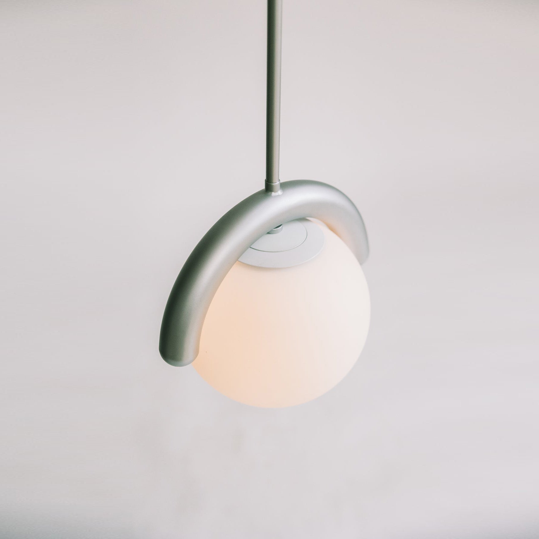 Liniowy żyrandol z falistą belką i trzema kulistymi światłami