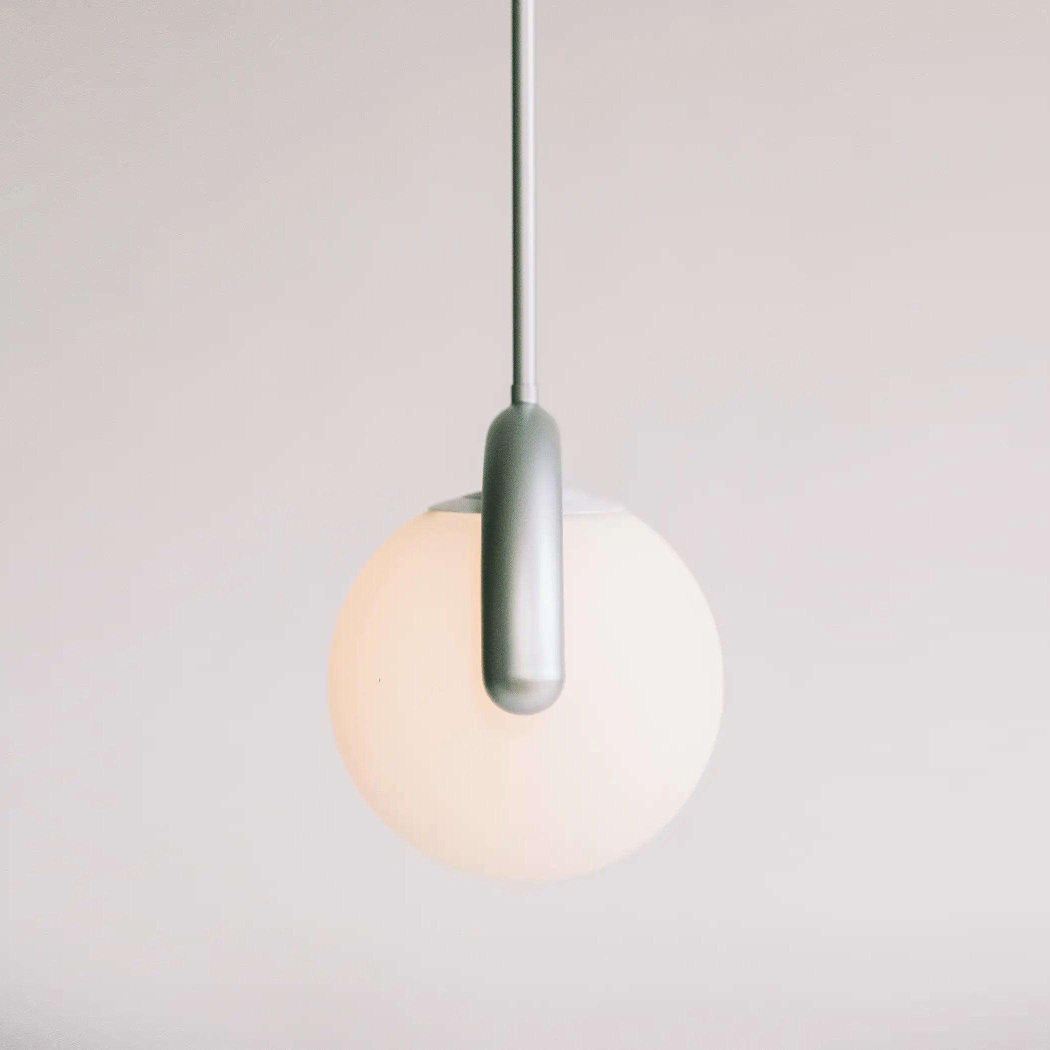 Liniowy żyrandol z falistą belką i trzema kulistymi światłami